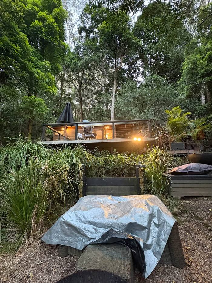 Bush cabin with warm deck lighting at dusk